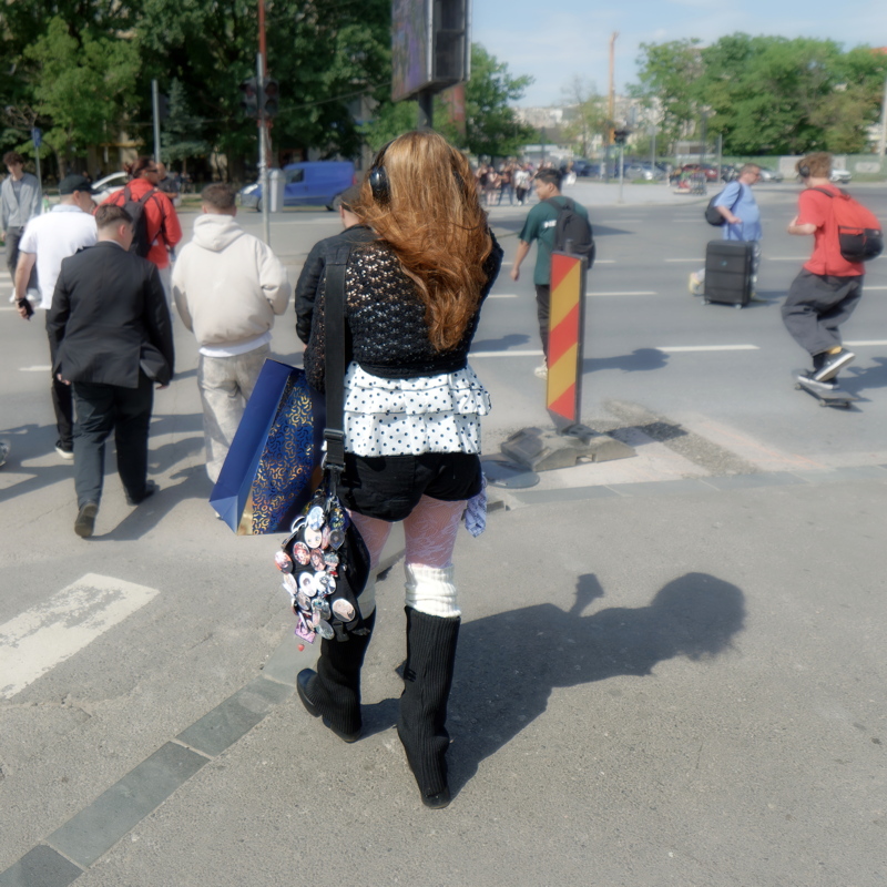 Girl wearing a black knit sweater with a white layered top, a black miniskirt, white patterned tights, and tall black leg warmers